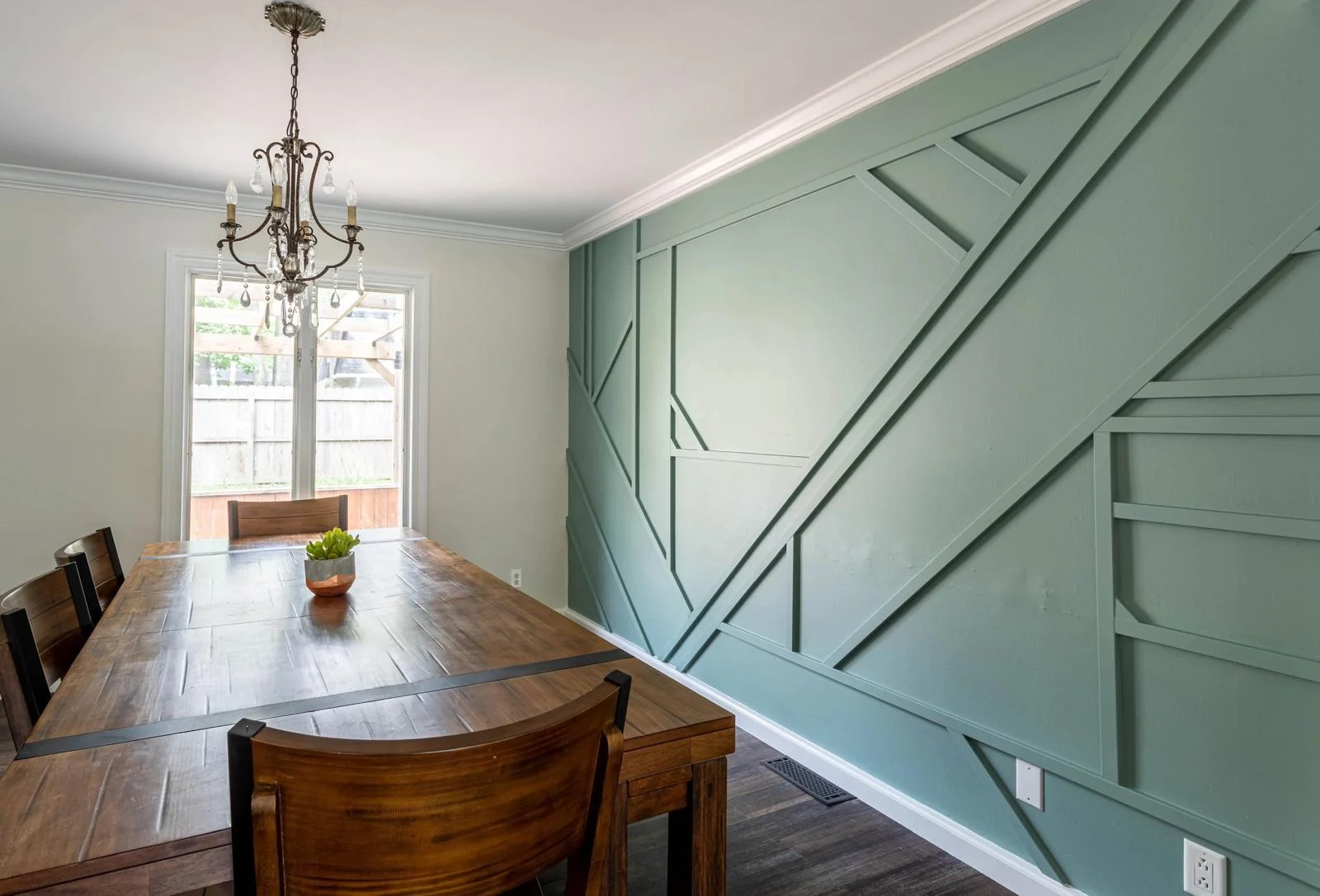 Sage green geometric wall paneling in a residential dining room